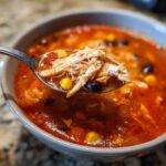 Close-up of a spoonful of Instant Pot Chicken Tortilla Soup showing shredded chicken, corn, and black beans.