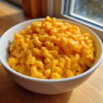 A close-up of a white bowl filled with creamy, bright orange Instant Pot Mac and Cheese.