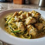 A close-up of Keto Chicken Alfredo featuring chunks of chicken in a creamy sauce over zucchini noodles.