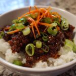 Close-up of Korean Ground Beef Bulgogi Bowls featuring savory ground beef over white rice, topped with shredded carrots and green onions.