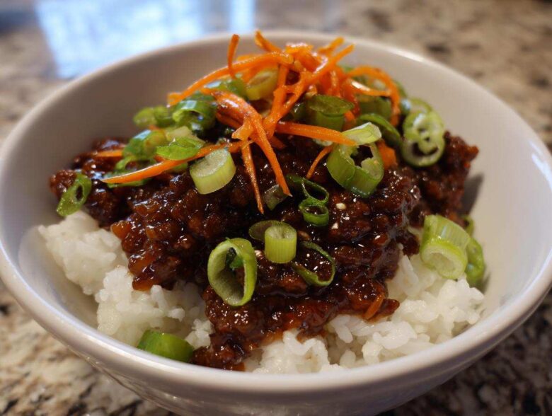 Close-up of Korean Ground Beef Bulgogi Bowls featuring savory ground beef over white rice, topped with shredded carrots and green onions.