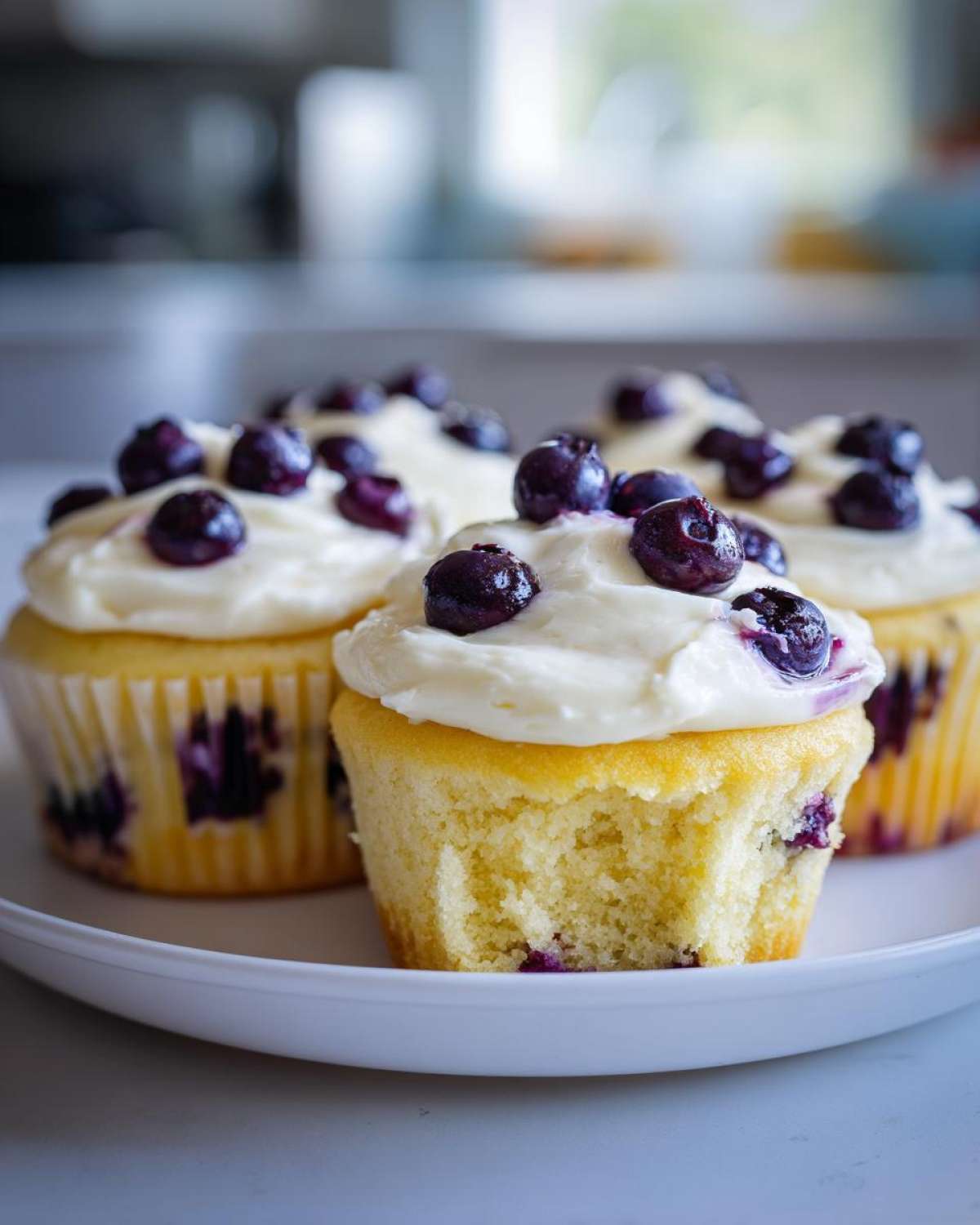 Close-up of Lemon Blueberry Cupcakes with Cream Cheese Frosting, one has a bite taken out.
