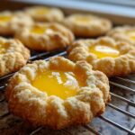 Close-up of freshly baked Lemon Curd Thumbprint Cookies with bright yellow filling cooling on a wire rack.