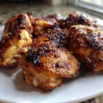 Close-up of several perfectly roasted Lemon Garlic Chicken Thighs with crispy, caramelized skin on a white plate.