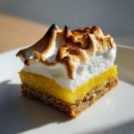 A close-up of one square Lemon Meringue Pie Bars with a thick, toasted meringue top.