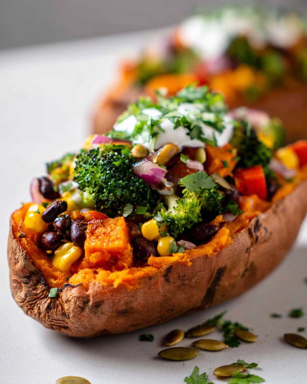 Close-up of a Loaded Veggie Stuffed Sweet Potato topped with broccoli, corn, beans, and sour cream.