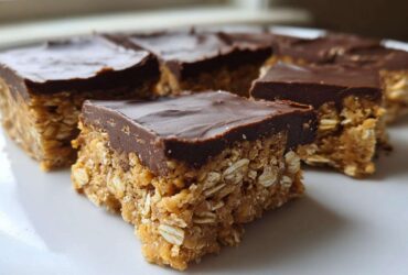 Close-up of several squares of No-Bake Chocolate Peanut Butter Oat Bars stacked on a white plate.