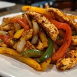 Close-up of seasoned chicken strips mixed with colorful sautéed peppers and onions, ready for One-Pan Chicken Fajitas.