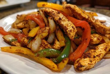 Close-up of seasoned chicken strips mixed with colorful sautéed peppers and onions, ready for One-Pan Chicken Fajitas.