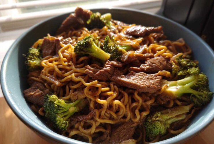 Close-up of One-Pot Beef and Broccoli Ramen Noodles coated in sauce, served in a blue bowl.