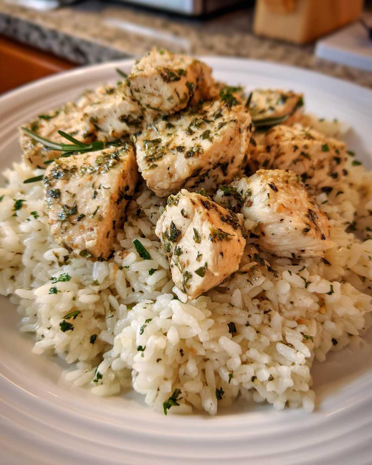 Close-up of cubed chicken breast seasoned with herbs served over fluffy white rice in One-Pot Chicken and Rice with Lemon and Herbs.