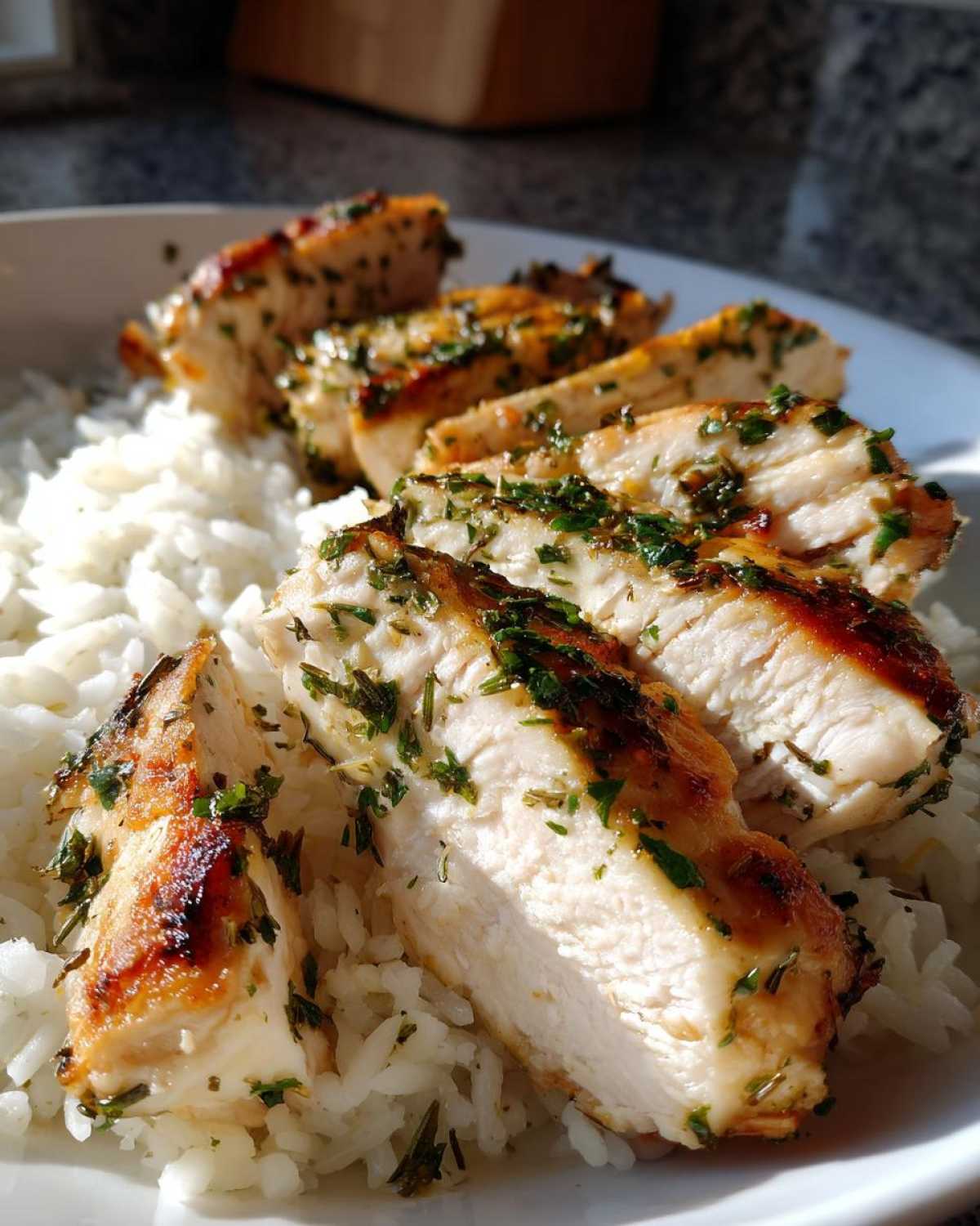 Close-up of sliced, herb-crusted chicken breast served over white rice from the one-pot chicken and rice recipe.