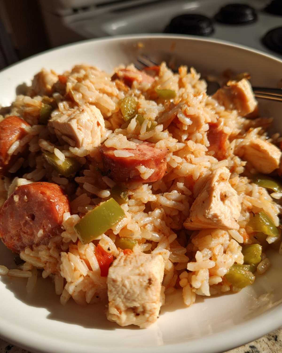 Close-up of a bowl filled with One-Pot Chicken Jambalaya featuring rice, chicken chunks, sliced sausage, and green peppers.