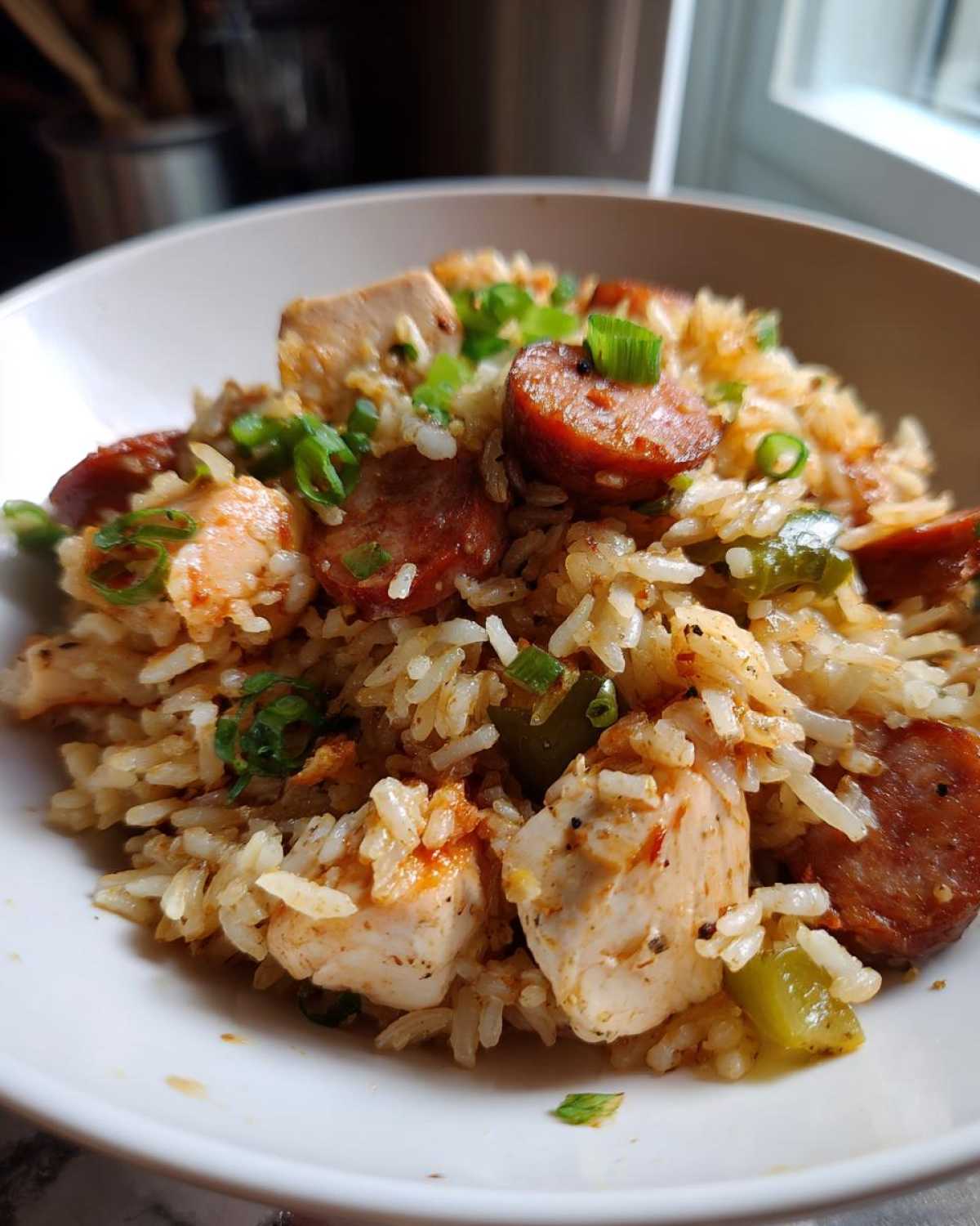 Close-up of a hearty serving of One-Pot Chicken Jambalaya with sausage, chicken chunks, and green onions.