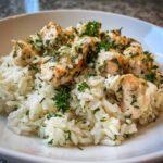 Close-up of tender chicken pieces served over fluffy white rice, generously topped with herbs for One-Pot Chicken and Rice with Lemon and Herbs.