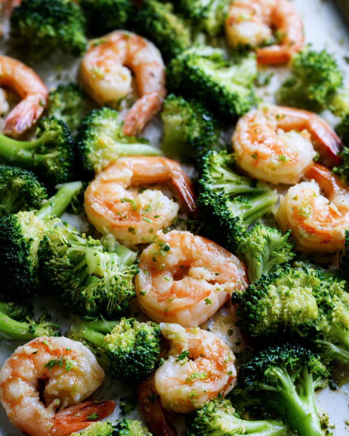 Close-up of cooked shrimp and bright green broccoli florets seasoned with garlic butter.