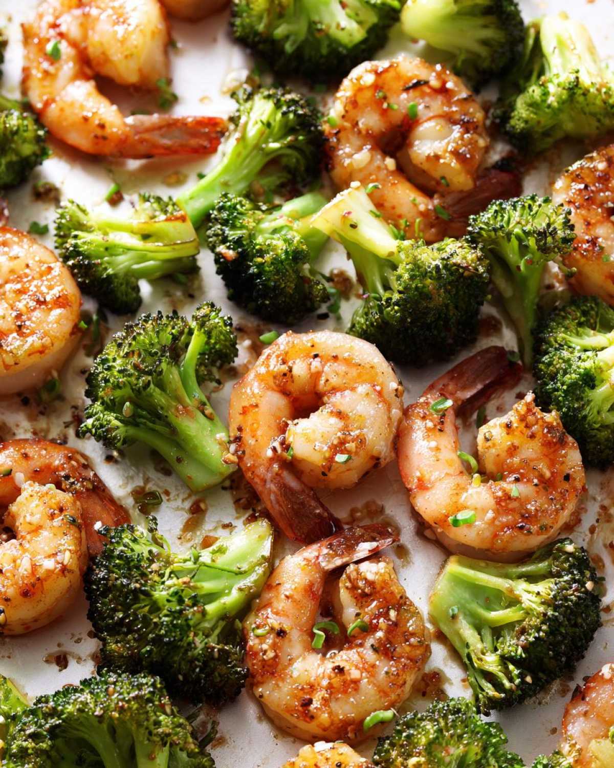 Close-up of perfectly cooked Sheet Pan Garlic Butter Shrimp and Broccoli seasoned with herbs.