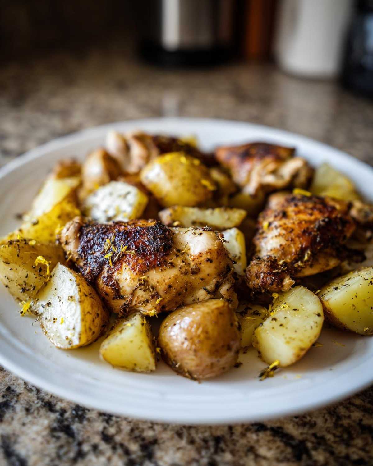 Close-up of crispy Sheet Pan Lemon Pepper Chicken and Potatoes served on a white plate.