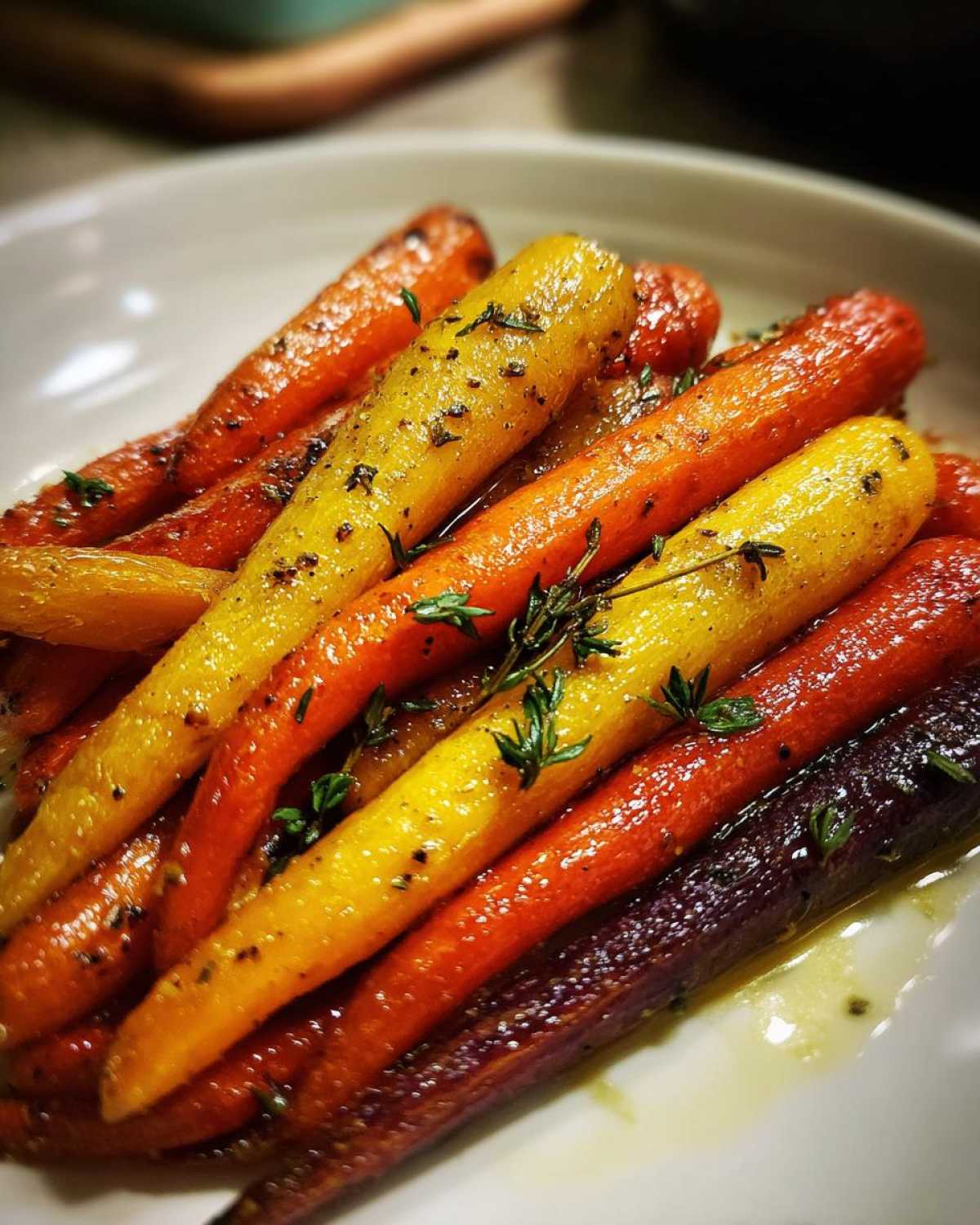 Close-up of glistening Sheet Pan Roasted Rainbow Carrots glazed with honey and seasoned with fresh thyme.