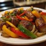 Close-up of browned sausages mixed with colorful bell peppers and onions from Sheet Pan Sausage and Peppers.