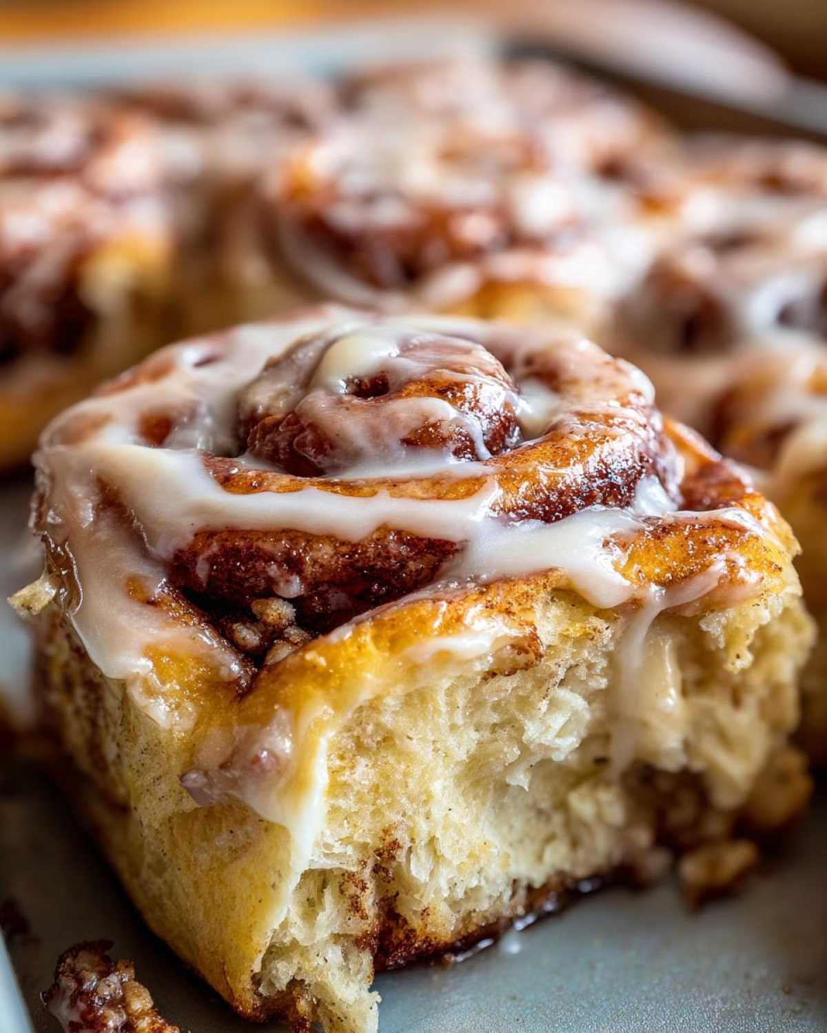 A close-up, soft-focus shot of one delicious Gluten-Free Cinnamon Roll with thick white icing, showing the fluffy interior.