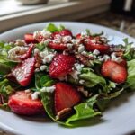 A vibrant bowl of Spring Mix Salad with Strawberries and Goat Cheese, topped with pecans.