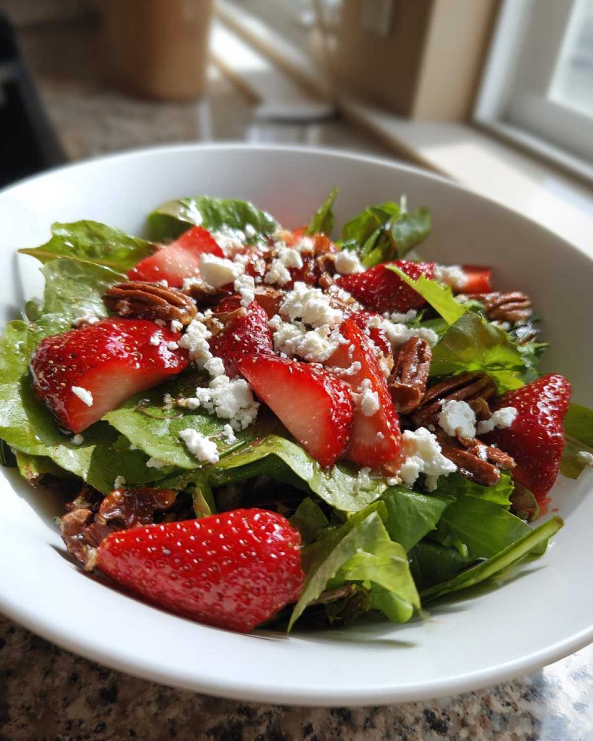 Close-up of a vibrant Spring Mix Salad with Strawberries and Goat Cheese, topped with pecans.