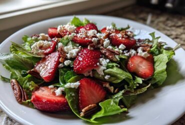 A vibrant bowl of Spring Mix Salad with Strawberries and Goat Cheese, topped with pecans.