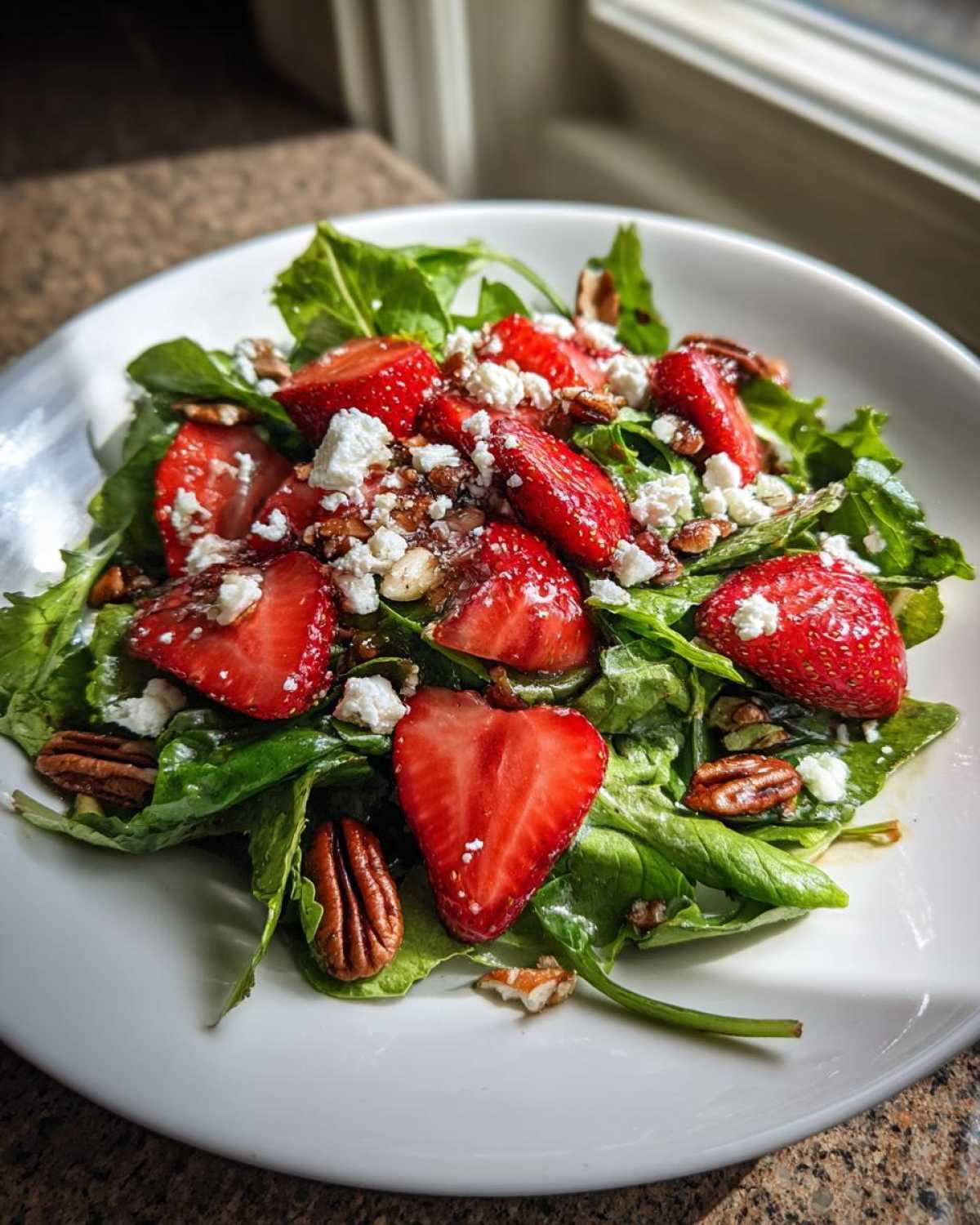 Close-up of a vibrant Spring Mix Salad with Strawberries and Goat Cheese, topped with pecans.