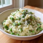 A close-up of creamy Spring Pea and Mint Risotto topped with grated Parmesan cheese and fresh mint.