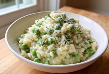 A close-up of creamy Spring Pea and Mint Risotto topped with grated Parmesan cheese and fresh mint.