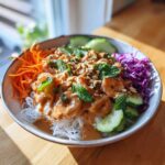 A colorful Spring Roll Bowl with Peanut Sauce, featuring shrimp, rice noodles, carrots, cucumber, and mint.