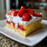 A delicious slice of Strawberry Shortcake Sheet Cake featuring yellow cake, strawberry filling, whipped cream, and fresh strawberries.