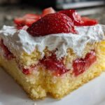 Close-up of a moist slice of Strawberry Shortcake Sheet Cake layered with strawberries and topped with whipped cream.