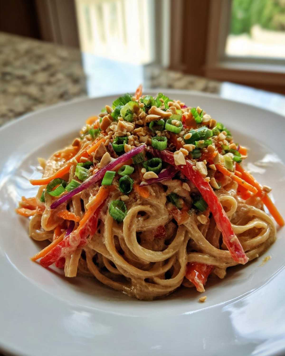 Close-up of Thai Peanut Noodles with Crunchy Veggies topped with peanuts and green onions.