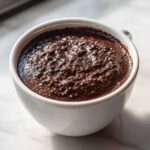 Close-up of thick, dark Vegan Chocolate Chia Pudding texture in a white serving bowl.