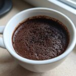 Close-up of rich, dark Vegan Chocolate Chia Pudding with a slight bubbly texture in a white mug.