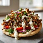 Close-up of a delicious Vegan Mushroom Shawarma piled high on pita bread with sauce and vegetables.
