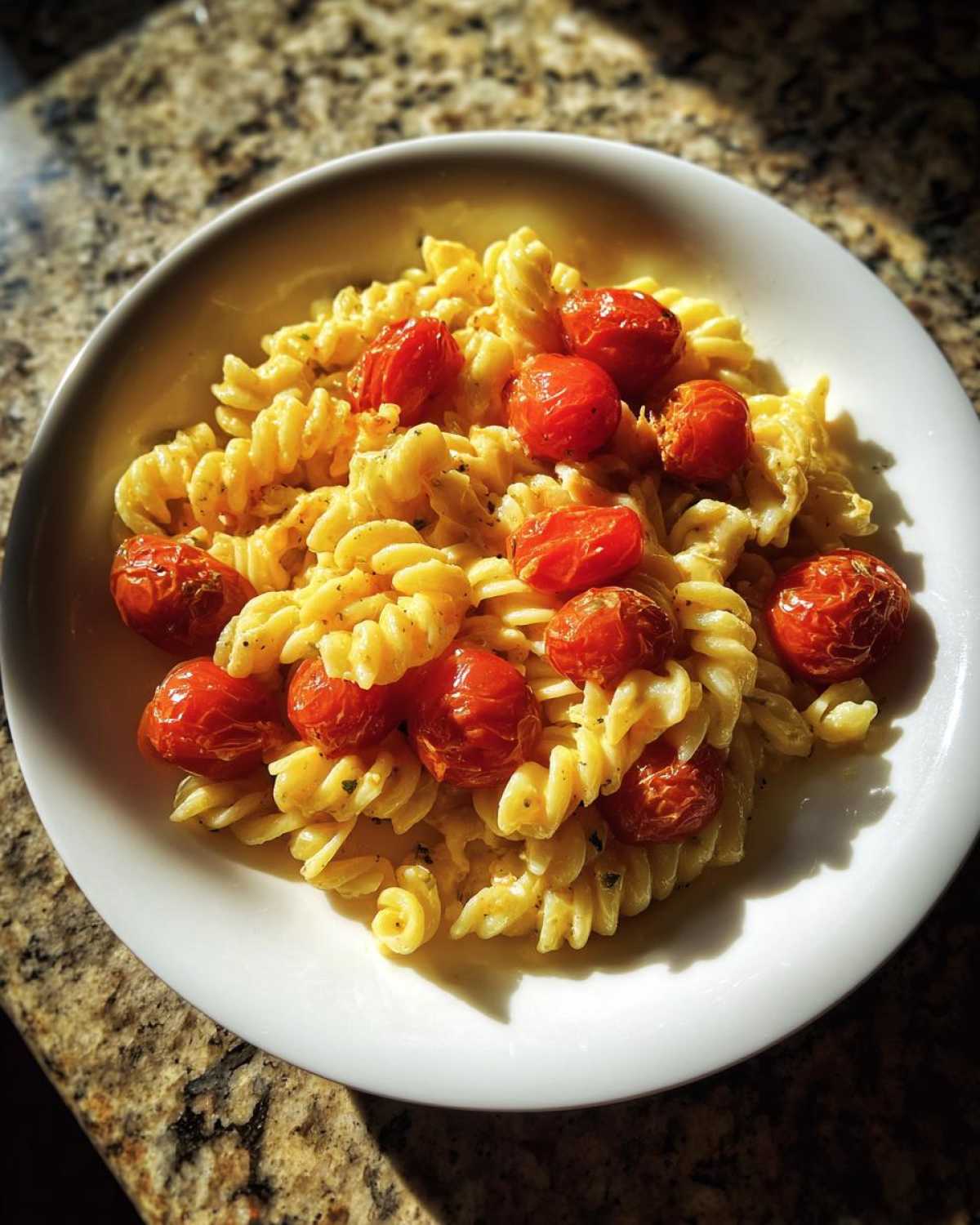 A white bowl filled with creamy Baked Feta Pasta with Cherry Tomatoes and fusilli pasta.