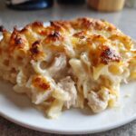 A generous serving of Cheesy Baked Chicken Alfredo with Crispy Top on a white plate, showing creamy sauce and browned cheese.