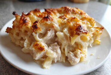 A generous serving of Cheesy Baked Chicken Alfredo with Crispy Top on a white plate, showing creamy sauce and browned cheese.