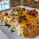 A close-up serving of Cheesy Baked Chicken with Cream Sauce, featuring a golden, bubbly cheese top and creamy interior.