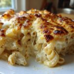 A close-up of a serving of Cheesy Chicken Alfredo Pasta Bake with Mozzarella, showing gooey cheese pulls and a browned top.