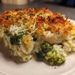 A close-up of a serving of Cheesy Chicken and Broccoli Pasta Bake, showing creamy sauce, broccoli florets, and a golden, crispy topping.