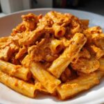 Close-up of Cheesy Chicken Pasta with Creamy Sauce featuring rigatoni pasta coated in a rich, orange sauce with visible chicken pieces.