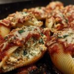 Close-up of baked Cheesy Chicken Stuffed Shells with Spinach, topped with melted mozzarella and marinara sauce.