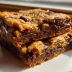 Two stacked, thick Chewy Chocolate Chip Cookie Bars showing gooey, melted chocolate centers.