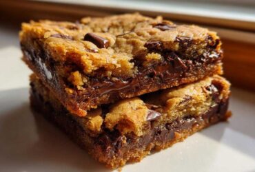 Two stacked, thick Chewy Chocolate Chip Cookie Bars showing gooey, melted chocolate centers.