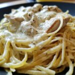 A close-up shot of delicious Creamy Alfredo Chicken Pasta featuring linguine coated in rich white sauce and topped with seasoned chicken pieces.