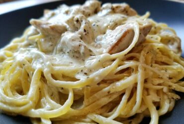 A close-up shot of delicious Creamy Alfredo Chicken Pasta featuring linguine coated in rich white sauce and topped with seasoned chicken pieces.